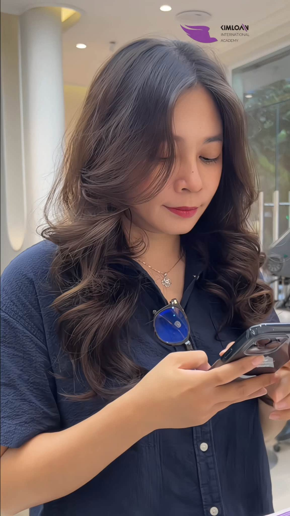 Khách hàng sử dụng điện thoại khoe mái tóc xoăn bung lơi góc nghiêng